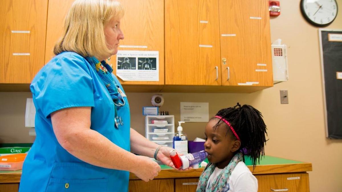 School nurse Sara Doberer watches the clock in between inhaler puffs as Shevaeh Peters takes her asthma treatment at Adams Elementary in Wichita, Kansas.