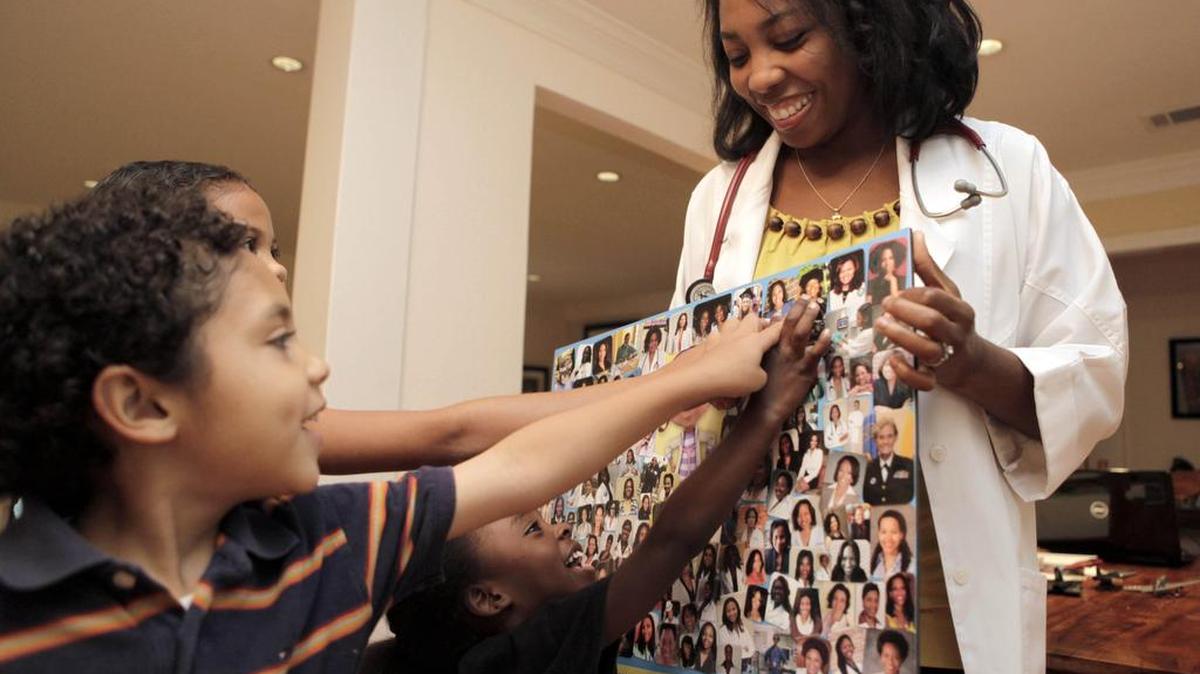 This June 7, 2012 photo shows Dr. Myiesha Taylor, right, holding a collage of fellow doctors supporting Disney Junior's animated series "Doc McStuffins." For black women whose own wish to practice medicine come true, the show is welcome affirmation. The doctors shown in the collage are graduates of schools including Harvard, Yale and Stanford and work in a range of specialities such as neurosurgery, orthopedic surgery and psychiatry.