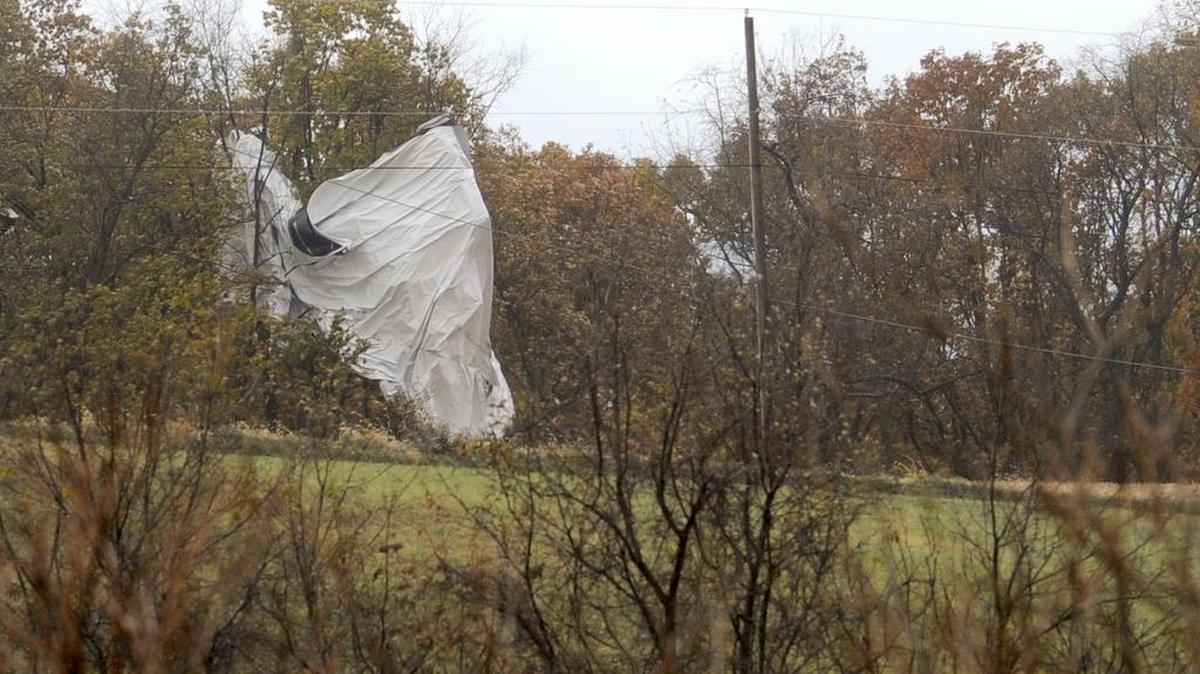 Part of an unmanned Army surveillance blimp hangs off a group of trees along County Line Road near the Montour and Lycoming county line, Wednesday, Oct. 28, 2015, after crash landing near Muncy, Pa. The blimp broke loose from its mooring in Maryland and floated over Pennsylvania for hours with two U.S. fighter jets on its tail, triggering blackouts across the countryside as it dragged its tether across power lines.
