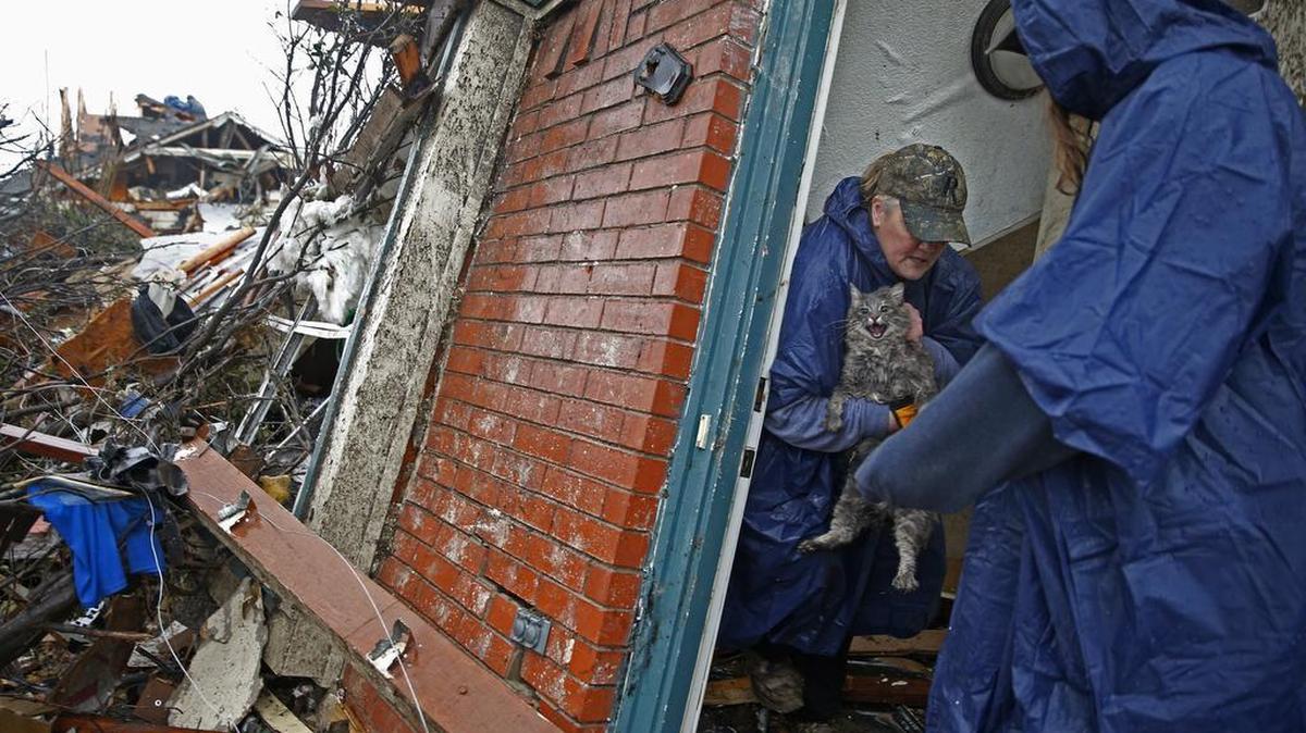 Pam Russell, left, rescues her cat, Larue, from her damaged home a day after a tornado hit in Rowlett, Texas, on Sunday. At least 11 people died and dozens were injured in apparently strong tornadoes that swept through the Dallas area and caused substantial damage this weekend.