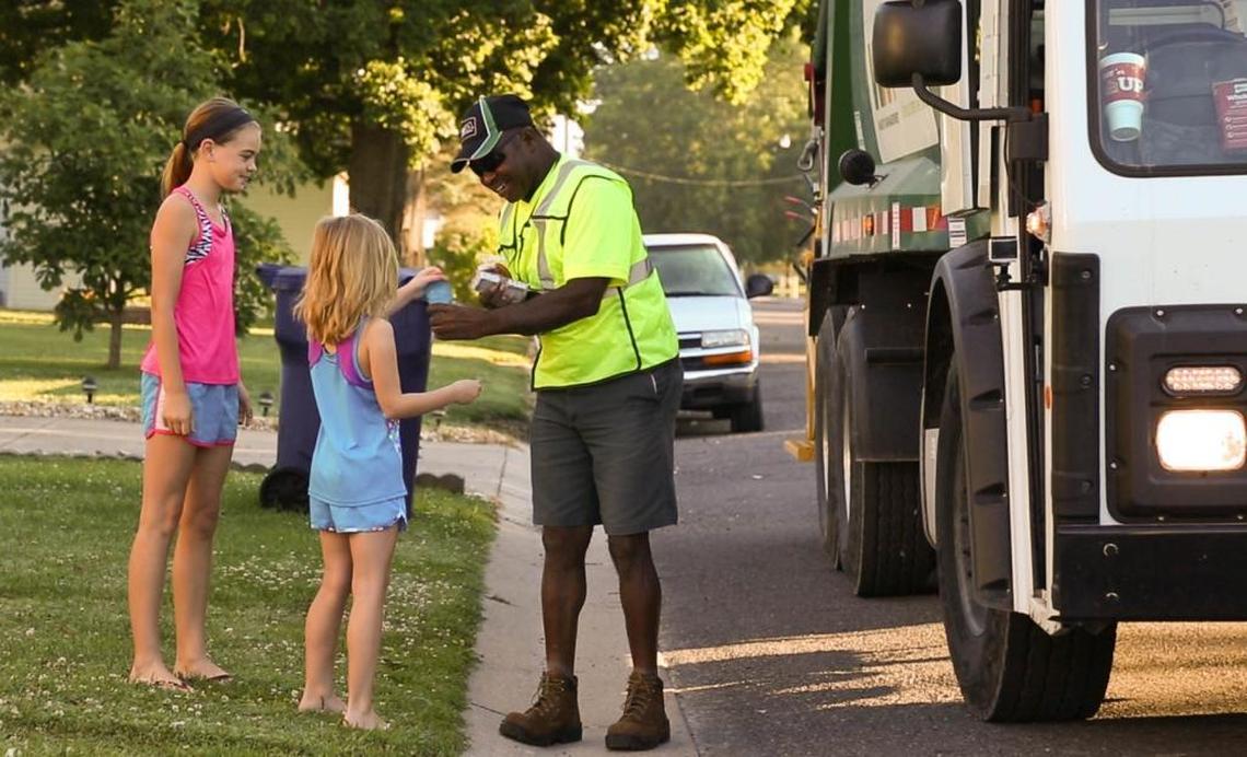 Avery Wuebbels (left) and her sister Adelyn Wuebbels gift sanitation worker Ira Campbell cold drinks and treats during his trash pickup route in Albers, IL on Tuesday, June 27. Albers Village Hall will be recognizing Campbell for his service to the community during the Albers Blast-Off Parade and Fireworks on Monday, July 3.