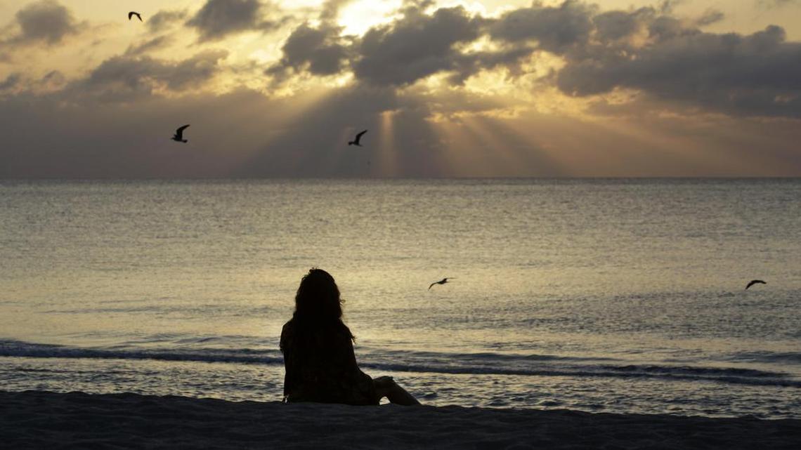 A woman meditates on the beach in Miami Beach, Fla.