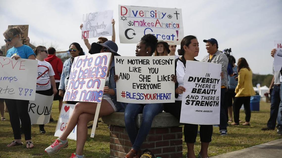 Protesters sit outside and across the street from a Donald Trump campaign rally, Saturday, March 5, 2016, in Orlando, Fla.