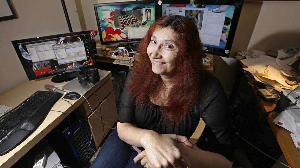In this Tuesday, Dec. 16, 2014, photo, longtime video game developer Becky Heineman poses for a photo at her workspace in Seattle. In the male-dominated world of multiplayer online games like “Grand Theft Auto,” “Halo,” and “Call of Duty,” many women say they've had to take drastic steps to escape harassment, stalking and violent threats from male players. Heineman, the founder of the Olde Skuul game studio in Seattle, used to be an aficionado of action-packed, violent games, but after being constantly harassed while playing highly-competitive games, she now plays simple, single-player games on her phone and computer.