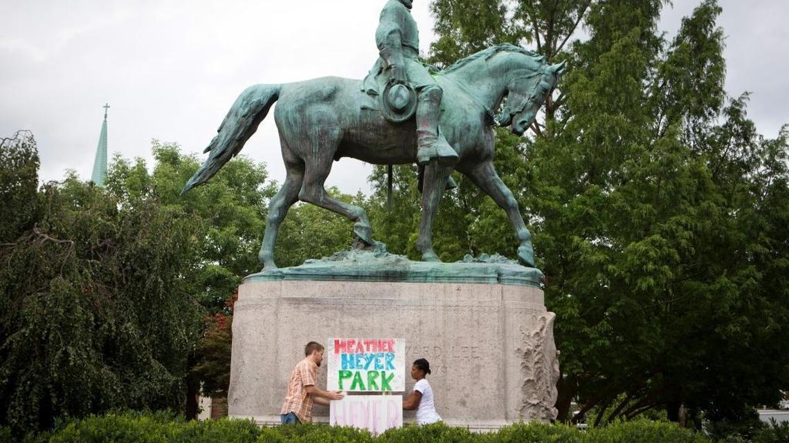 Tom Lever, 28, and Aaliyah Jones, 38, both of Charlottesville, put up a sign that says "Heather Heyer Park" at the base of the Confederate general Robert E. Lee monument in Emancipation Park Tuesday, Aug. 15 in Charlottesville, Va.