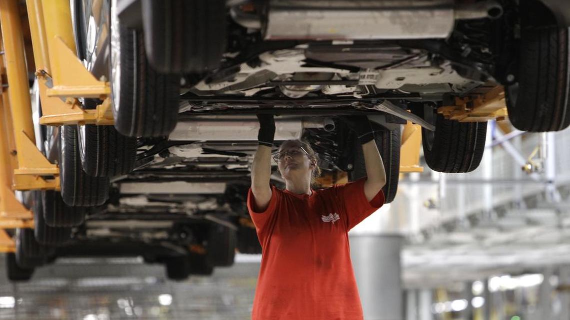 In this March 17, 2011 photo, a line worker checks a 2012 Ford Focus on the assembly line at the Michigan Assembly Plant in Wayne, Mich.