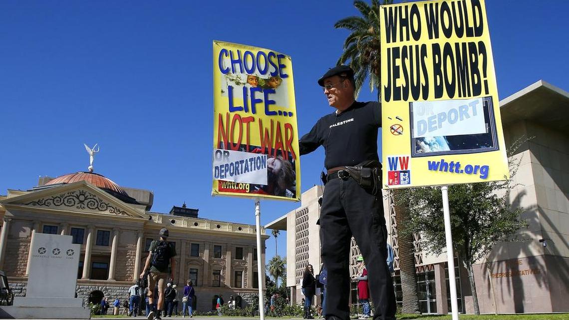 The debate on Syrian refugees crosses many lines, as seen in the posters displayed by Tom Compton of Arizona, who recently showed his support of allowing refugees.