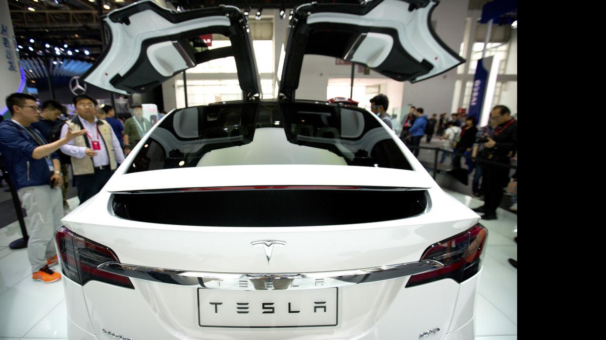 A visitor looks at a Tesla Model X on display at the Beijing International Automotive Exhibition in Beijing on April 26. (AP Photo/Mark Schiefelbein)