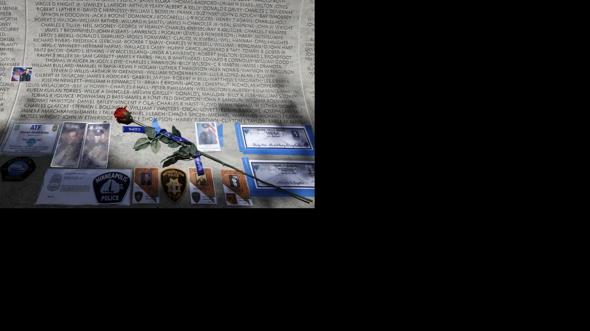 FILE - In this May 13, 2013 file photo, a rose is placed at the wall with the names of fallen police officers at the National Law Enforcement Officers Memorial in Washington during the National Police Week. The number of law enforcement officers killed by firearms in the U.S. jumped by 56 percent this year and included 15 ambush assaults, according to a report released Tuesday. The annual report by the nonprofit National Law Enforcement Officers Memorial Fund found that 50 officers were killed by guns this year, compared to 32 in 2013.(AP Photo/Jose Luis Magana, File)