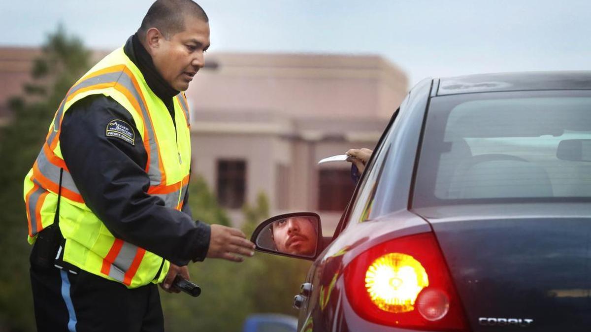 A security detail checks employee ID badges as they enter the Inland Regional Center complex in San Bernardino, Calif., on Monday. Employees returned to the center, many for the first time, following a Dec. 2 mass shooting that killed 14 people.