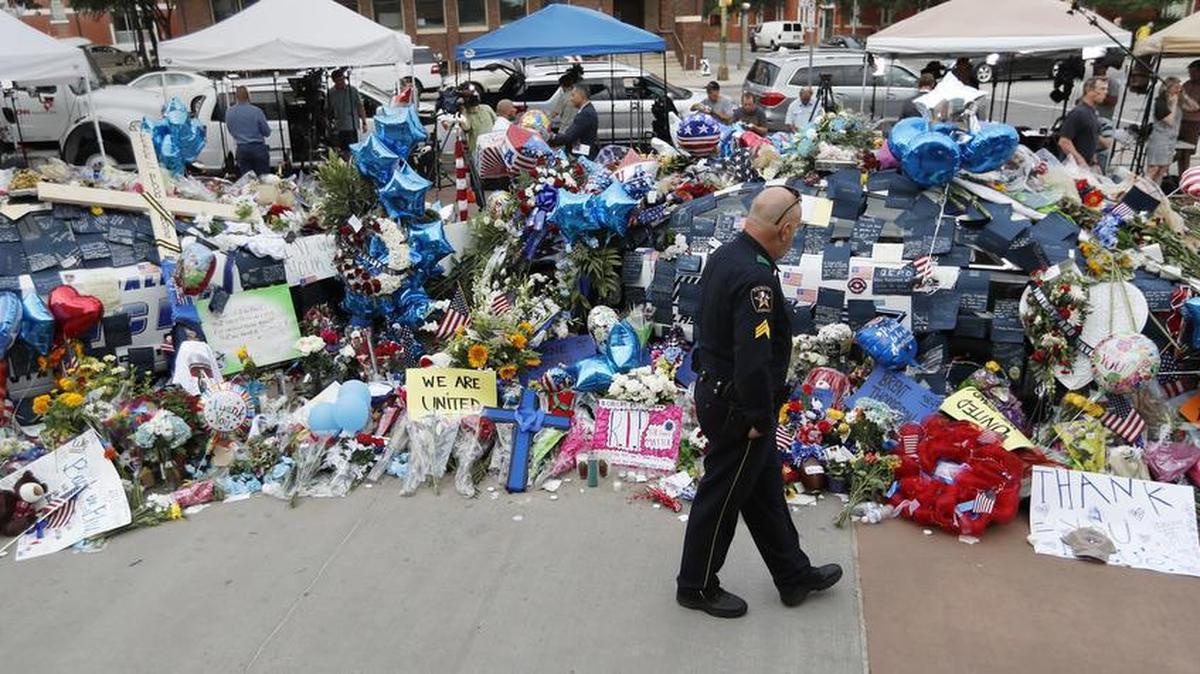 A policeman visits a makeshift memorial at the Dallas police headquarters, Monday, July 11, 2016, in Dallas. Five police officers were killed and several injured during a shooting in downtown Dallas last Thursday night.