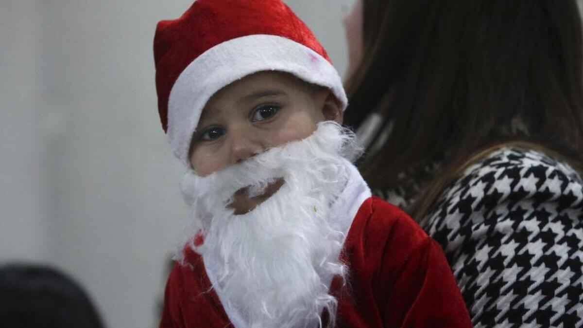 A Palestinian boy wears a Santa Claus costume while waiting with his family for the Auxiliary Bishop of the Latin Patriarch of Jerusalem Giacinto-Boulos Marcuzzo to start Mass at Deir Al Latin Holy Family Catholic Church in Gaza City, Sunday, Dec. 18, 2016.