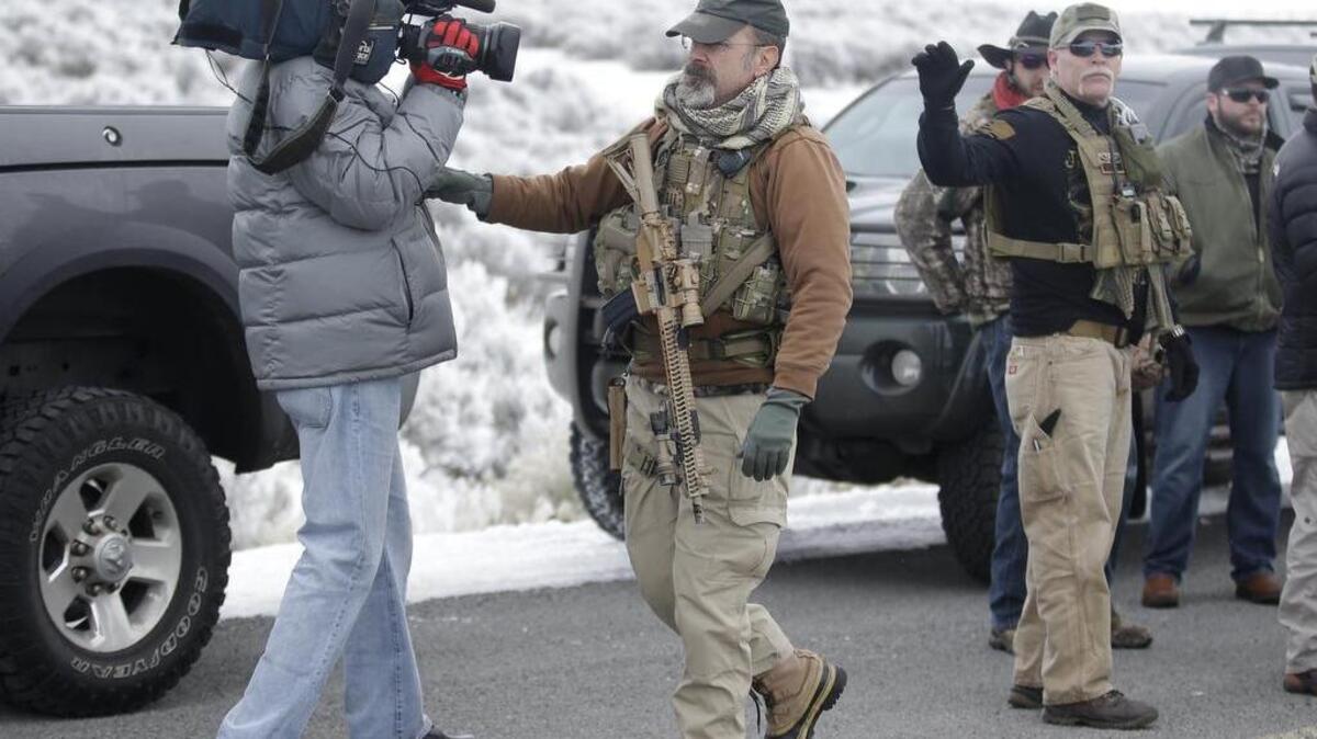 A man standing guard pushes a videographer aside after members of the "3% of Idaho" group along with several other organizations arrived at the Malheur National Wildlife Refuge near Burns, Ore., on Jan. 9, 2016.