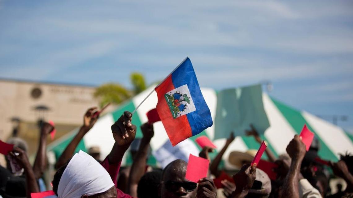 A Haitian holds a national flag outside the U.S. embassy where dozens gathered to protest against President Donald Trump's recent disparaging comments about Haiti and African nations, in Tabarre, a district of Port-au-Prince, Haiti, Thursday, Jan. 18, 2018.