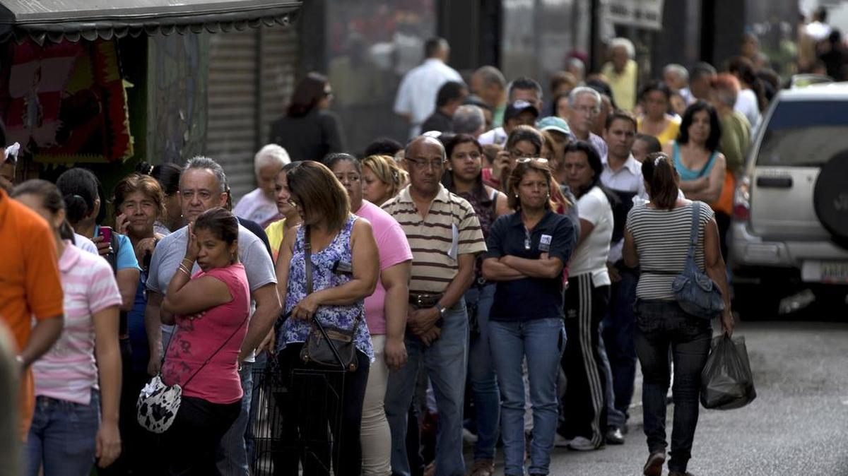 In this Jan. 8, 2015, photo, shoppers line up outside of a supermarket in downtown Caracas, Venezuela. Venezuelans continue to struggle to find basic goods including detergent and sugar. Venezuela is in crisis, its economy shrinking, its oil wealth no longer generating the kind of money the country needs to import products, its farms and factories no longer producing enough to satisfy its citizens.