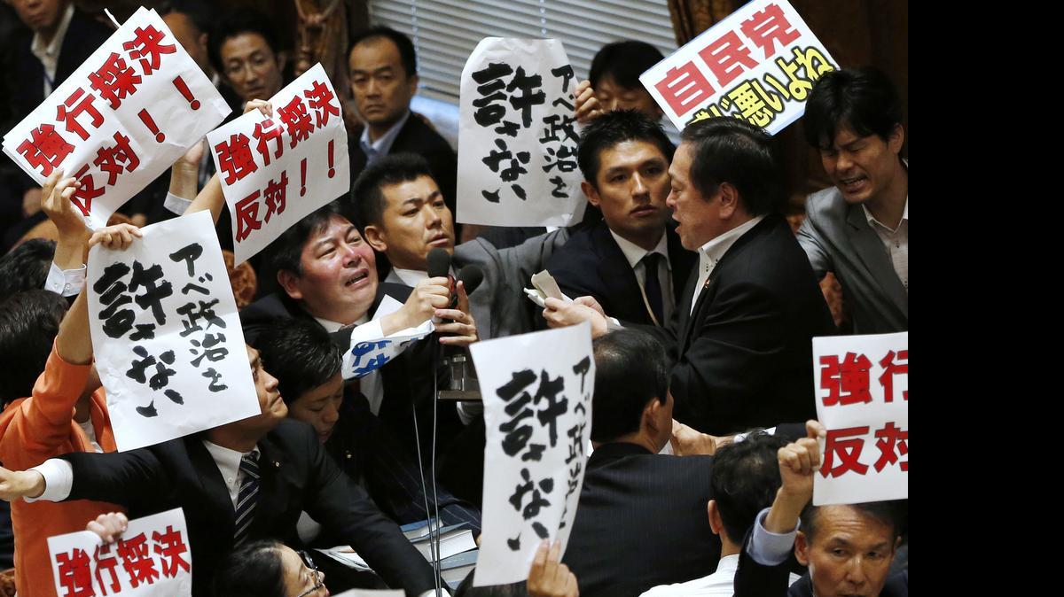 
Opposition lawmakers surround Yasukazu Hamada, right, chairman of the lower house special committee on security legislation, as Hamada continues the committee proceedings at the parliament in Tokyo on Wednesday. The parliamentary committee has approved a package of highly controversial security legislation in a vote forced by Prime Minister Shinzo Abe’s ruling bloc disrupted by opponents’ massive protests. The banners held by opposition lawmakers read “Oppose forcible passage (of the bills)” and “Never forgive Abe’s politics.”
