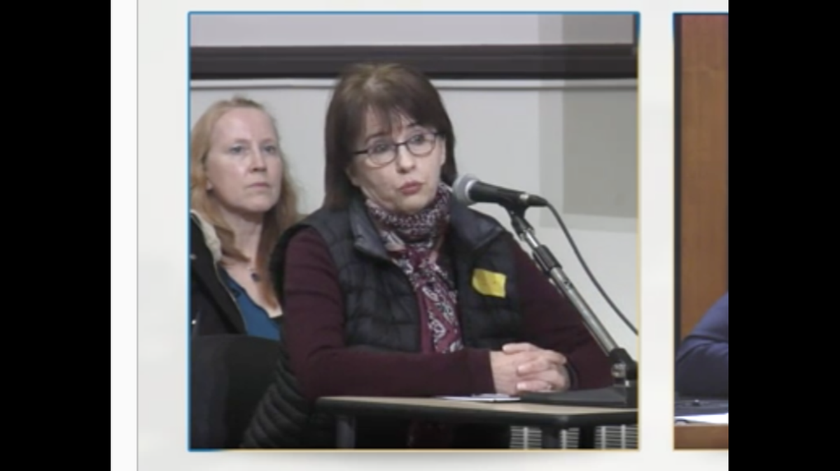 A woman wears a yellow protest badge at a meeting in Montreal.