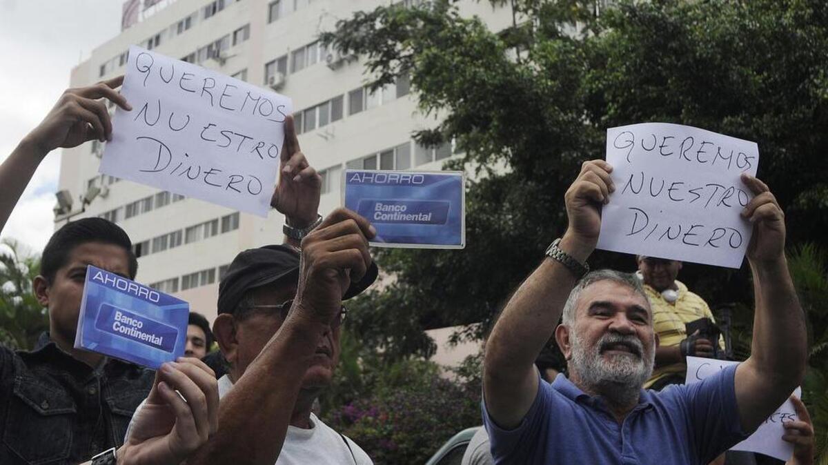 
Clients with accounts in the Banco Continental hold up signs saying “We want our money” as they protest outside of a bank branch in Tegucigalpa, Honduras, Monday, Oct. 12, 2015. 
