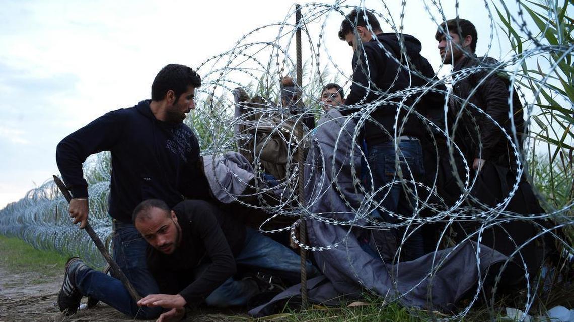 
 Syrian refugees cross into Hungary underneath the border fence on the Hungarian-Serbian border near Roszke, Hungary, on Aug. 26, 2015. Many of the migrants flooding Europe to escape war or poverty are scrapping their true nationalities to improve their chances of asylum, many claiming to be Syrian. 
