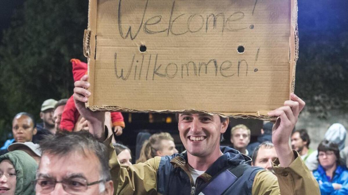 
Am man holds a cardboard with a ‘Welcome’ slogan during the arrival of refugees at the train station in Saalfeld, central Germany, Sept. 5, 2015. Hundreds of refugees arrived in a train from Munich to be transported by busses to an accomodation centre.
