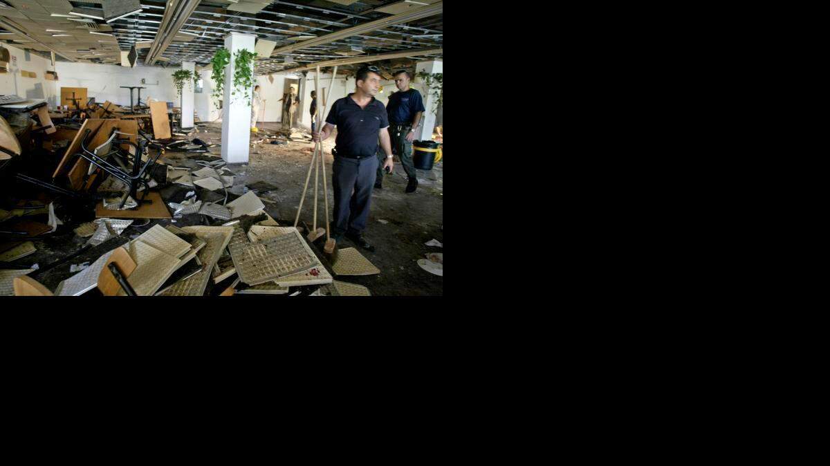 
Workers clean the inside of a cafeteria hours after a bomb exploded at Hebrew University in Jerusalem on July 31, 2002 , killing nine, four of them Americans, and wounding more than 70. 
