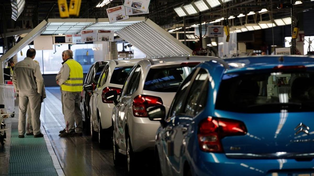 Workers stand next to cars at the French car manufacturer PSA Peugeot Citroen in Aulnay-sous-Bois, north of Paris.