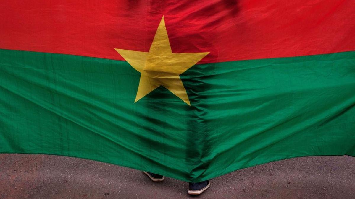 A man stand in front of the Burkina Faso nationals flag during a memorial ceremony for the victims of the recent hotel attack were extremist killed foreigners and Burkina Faso nationals, in Ouagadougou on Saturday, Jan. 23, 2016. Burials have begun for the 10 Burkina Faso nationals killed in last week's attack on a cafe and hotel in the capital, Ouagadougou, highlighting the local toll suffered in the latest West African country targeted by Islamic extremists.