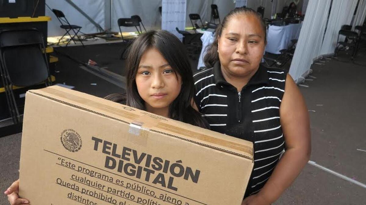 
Tomasa López and her 11-year-old daughter Susana show off the new digital television set they picked up Aug. 6. Mexico's government hopes to give away 10 million 24-inch sets by the end of the year.
