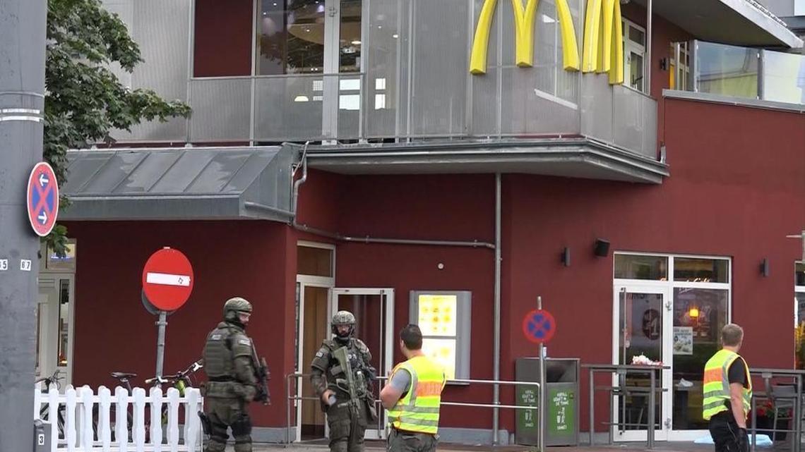 In this image taken from video, police officers stand outside a McDonald's restaurant near the Olympia mall in Munich on Friday. Police said a manhunt was underway Friday for the gunmen who opened fire at the shopping mall, killing and wounding several people.