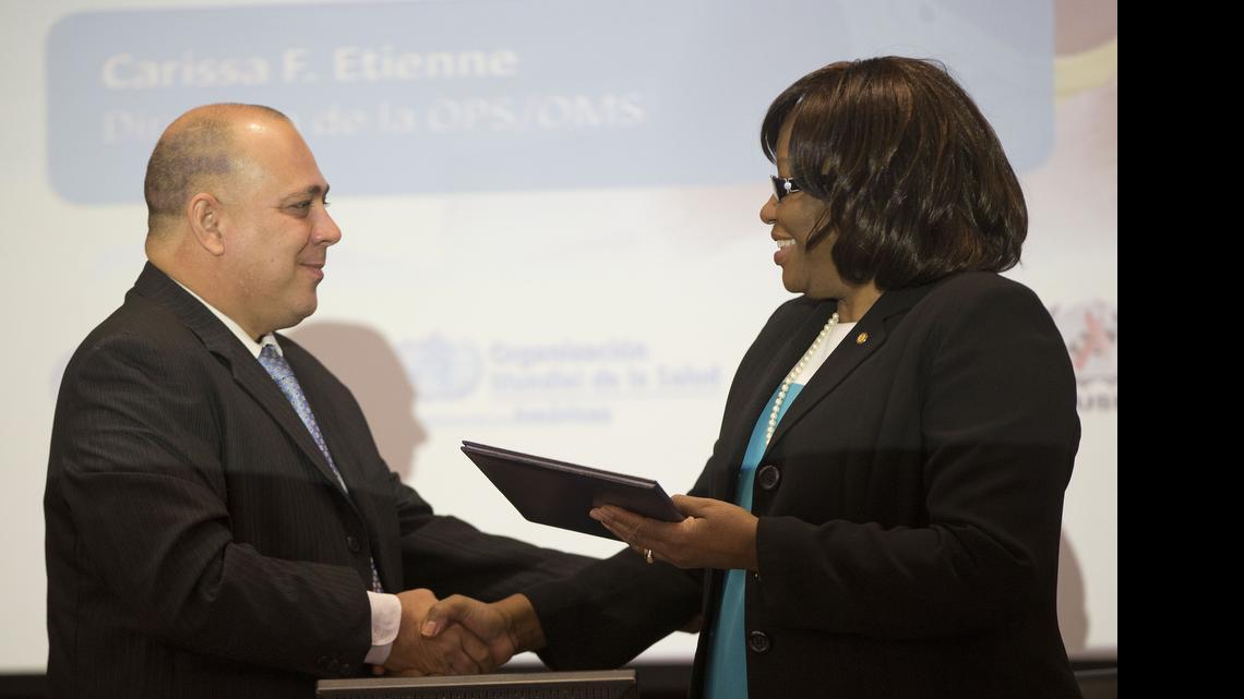 
Dr. Carissa F. Etienne, Dir. Pan America Health Organization (PAHO), right, shakes hands with Dr. Roberto Tomas Morales Ojeda, Minister of Health, Cuba, left, at the World Health Organization (WHO) during a certificate presentation announcing that Cuba is world's first country to receive validation of having eliminated mother-to-child transmission of HIV and Syphilis, during news conference at Pan American Health Organization/World Health Organization (PAHO/WHO) headquarters in Washington, Tuesday, June 30, 2015. 
