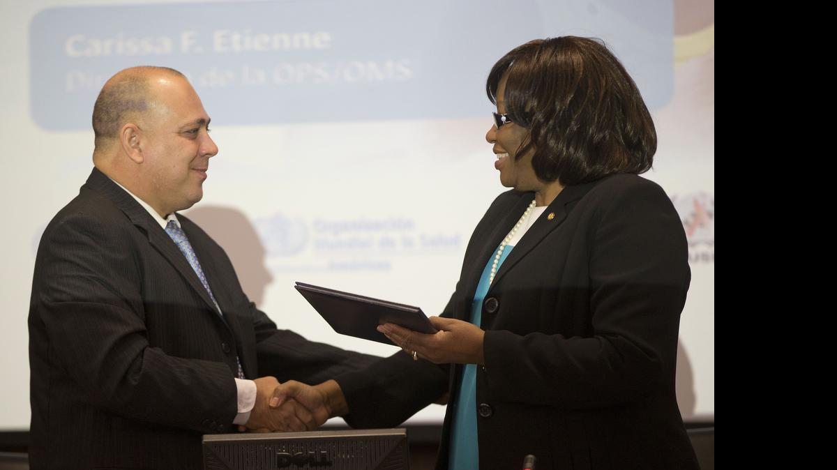 
Dr. Carissa F. Etienne, Dir. Pan America Health Organization (PAHO), right, shakes hands with Dr. Roberto Tomas Morales Ojeda, Minister of Health, Cuba, left, at the World Health Organization (WHO) during a certificate presentation announcing that Cuba is world's first country to receive validation of having eliminated mother-to-child transmission of HIV and Syphilis, during news conference at Pan American Health Organization/World Health Organization (PAHO/WHO) headquarters in Washington, Tuesday, June 30, 2015. 
