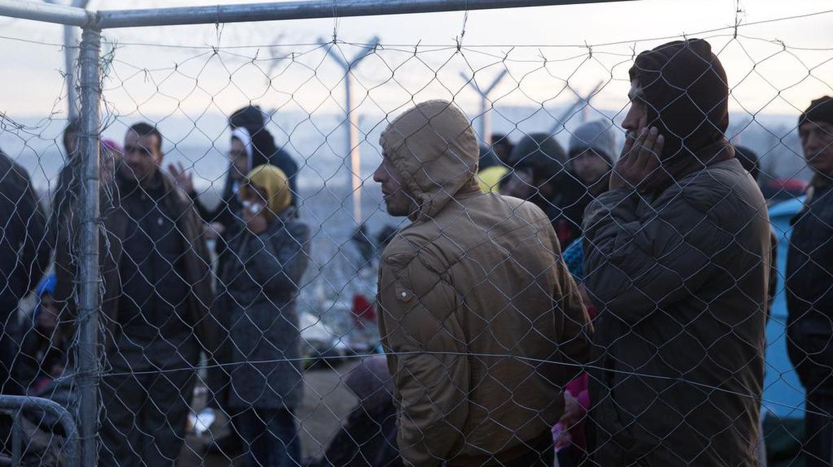 Refugees stand near the border fence as they wait to be allowed to cross the border into Macedonia in the northern Greek border station of Idomeni, Sunday, March 6, 2016.