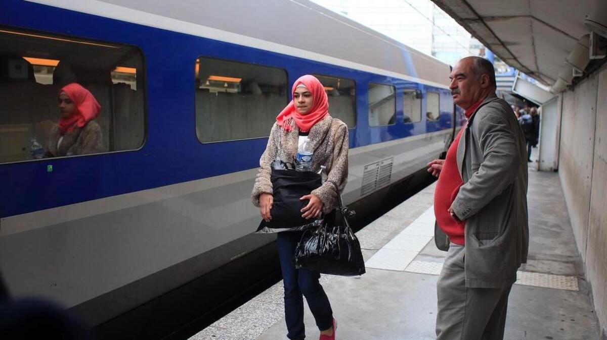 
Syrian refugee Isra Abomosa, 18, carries belongings before boarding a train to Vannes, France, in a Paris railway station on Thursday, Sept. 24, 2015. 
