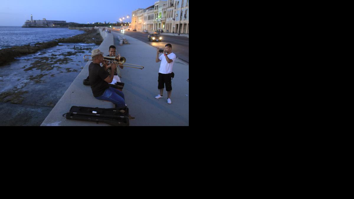 
In this July 8, 2013, photo, musicians play trombones as a tourist from Colombia takes their picture along the Malecon in Havana, Cuba. President Barack Obama’s announcement Wednesday, Dec. 17, 2014, of plans to re-establish diplomatic ties with the Caribbean nation gives hope to airlines, hotel chains and cruise companies _ all which have been quietly eyeing a removal of the travel ban _ that they soon will be able to bring tourists to Cuba.
