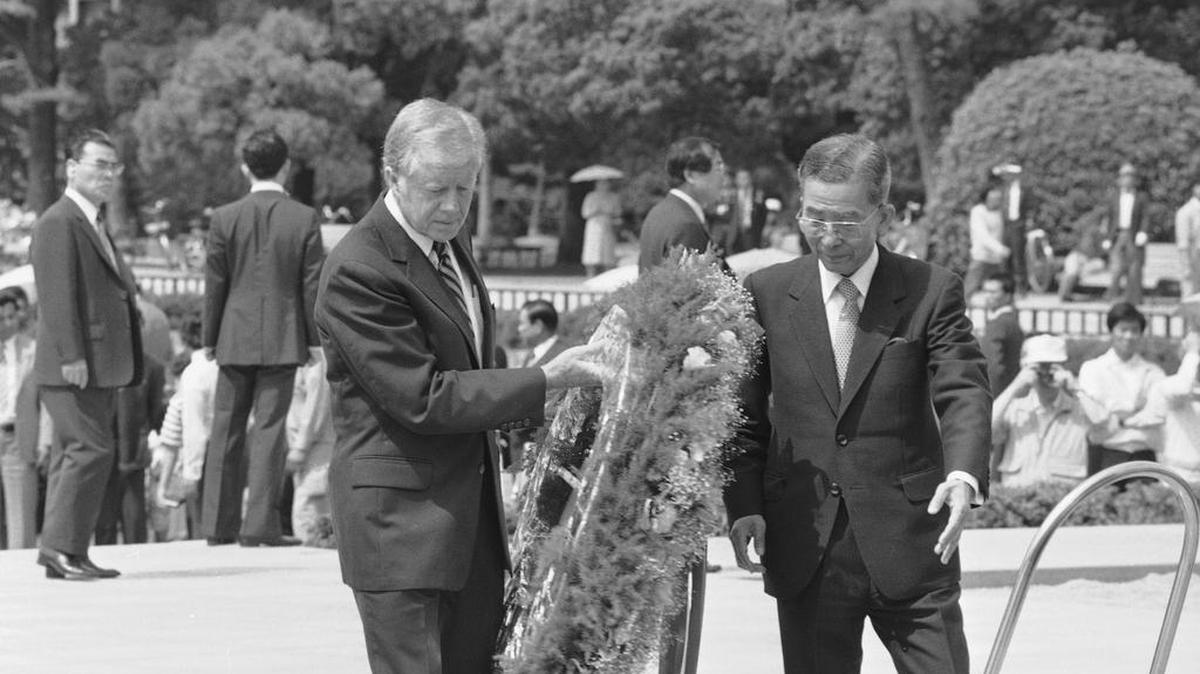 Guided by Hiroshima Mayor Takeshi Araki, former U.S. President Jimmy Carter, left, carries a flowered wreath to place at the memorial cenotaph, a monument that contains the names of those who died in the 1945 atomic bombing of Hiroshima, western Japan, May 25, 1984.