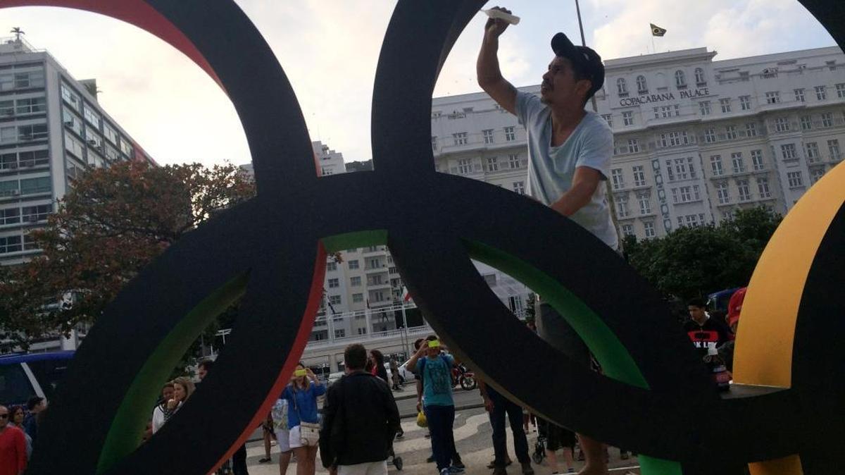 A worker puts finishing touches on Olympic rings along Copacabana beach, where tourists and locals stop to take selfies in Rio de Janeiro on Friday, July 22, 2016. Rio is ready to host the games after a bumpy start.