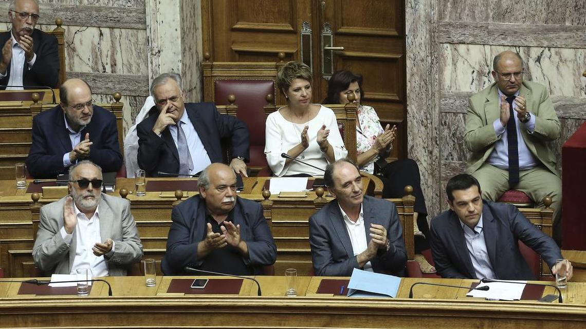 
Greek Prime Minister Alexis Tsipras, front right, acknowledges applause after delivering his speech during a parliamentary session in Athens, Friday, Aug. 14, 2015. Greek lawmakers2 approved their country's draft third bailout in a parliamentary vote that relied on opposition party support and saw the government coalition suffer significant dissent. 

