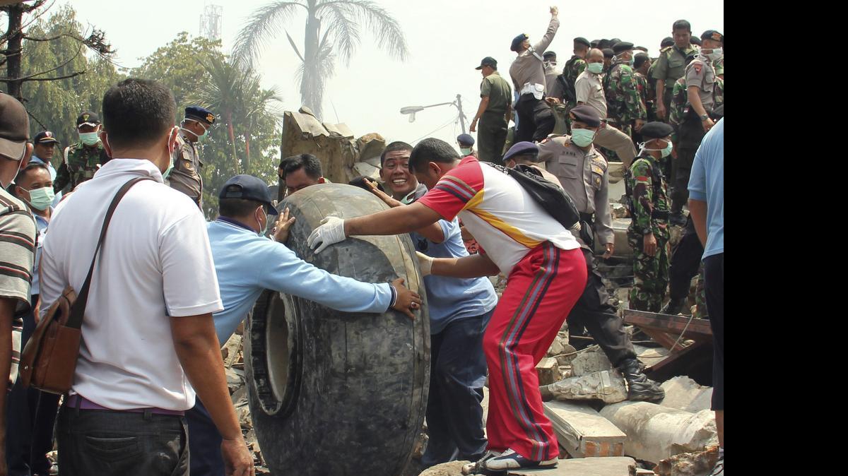 
Military personnel remove an aircraft wheel at the site where an air force cargo plane crashed in Medan, North Sumatra, Indonesia, Tuesday, June 30, 2015. An Indonesian air force Hercules C-130 plane with 12 crew aboard has crashed into a residential neighborhood in the country's third-largest city Medan. 
