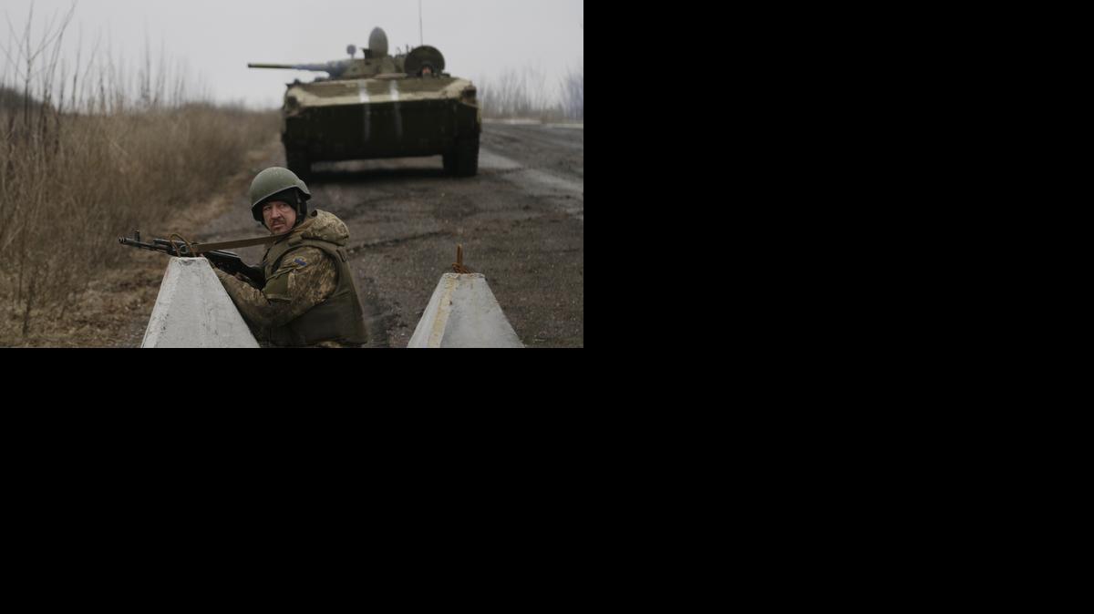 
Ukrainian troops guard a roadblock between the towns of Vuhlehirsk and Debaltseve, Ukraine on Friday, Feb. 6, 2015, as a convoy of buses travel to evacuate civilians caught in the crossfire of fighting between government troops and Russian-backed separatists. 
