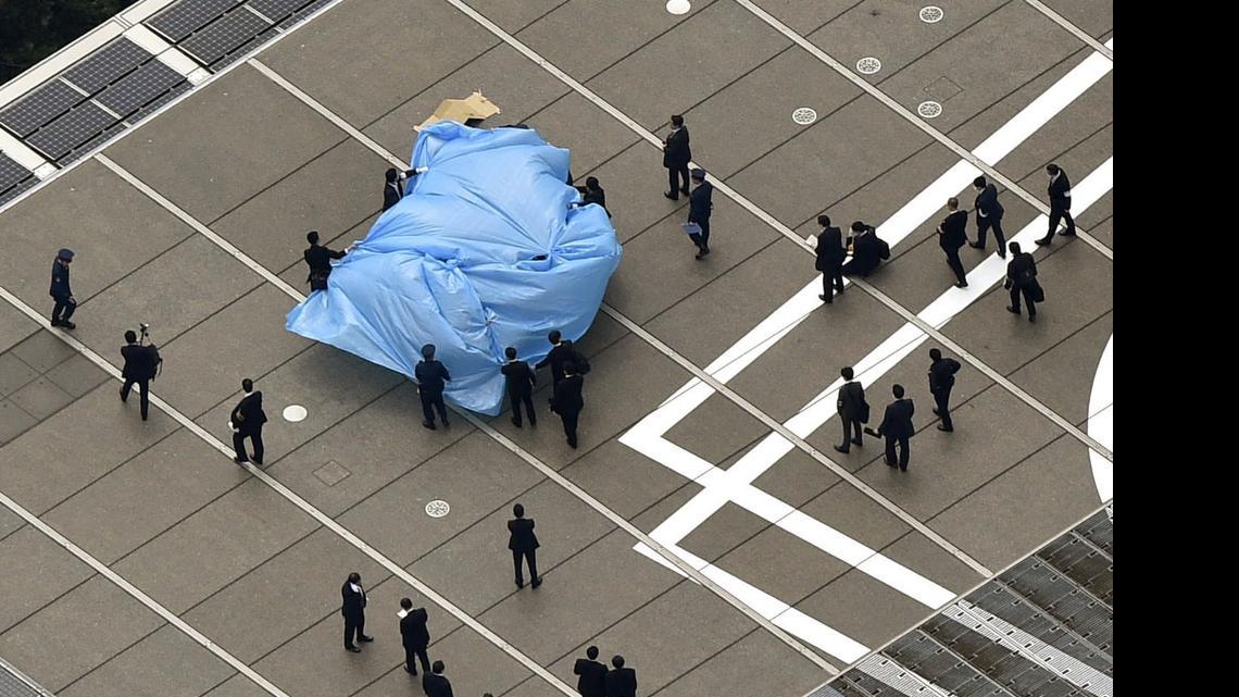 
Investigators gather around a small drone covered with blue sheets, on the roof of Prime Minister Shizo Abe's official residence in Tokyo Wednesday, April 22, 2015. Japanese authorities were investigating Wednesday after the small drone reportedly containing traces of radiation was found on the roof of the prime minister's office, sparking concerns about drones and their possible use for terrorist attacks.
