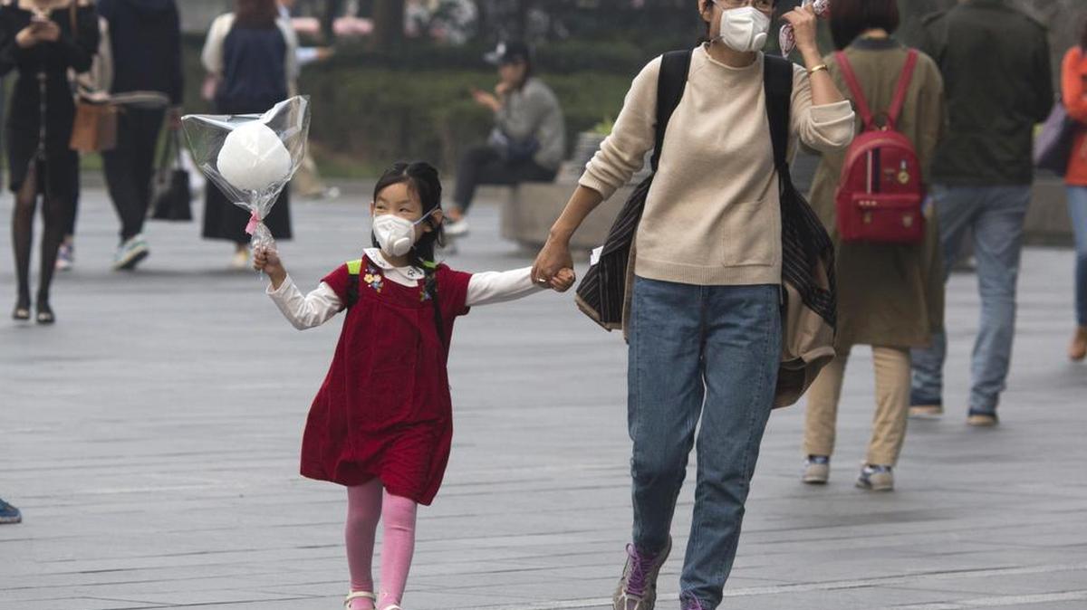 A woman and child wear masks during a hazy day in Beijing Friday, Oct. 14, 2016. China has lifted regulations limiting each family to one child, but many exhausted parents say they aren’t interested in having more kids.