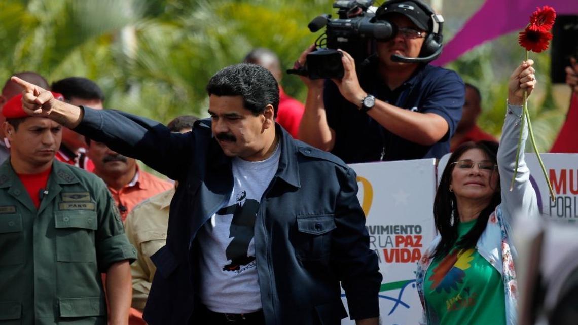 Venezuela's President Nicolas Maduro, left, and his wife Cilia Flores greet supporters upon their arrival for a rally outside Miraflores Presidential palace in Caracas, Venezuela, Saturday, Feb. 22, 2014.