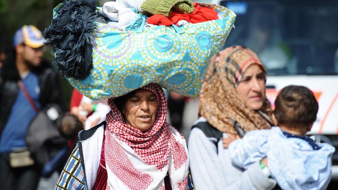 
A refugee woman from Syria carries a bag with personal things atop her head at a tent village for migrants at the Donnersberg bridge close to the central train station in Munich on Sunday Sept. 13, 2015. Hundreds of thousands of Syrian refugees and others are still making their way slowly across Europe, seeking shelter where they can, taking a bus or a train where one is available, walking where it isn’t. 
