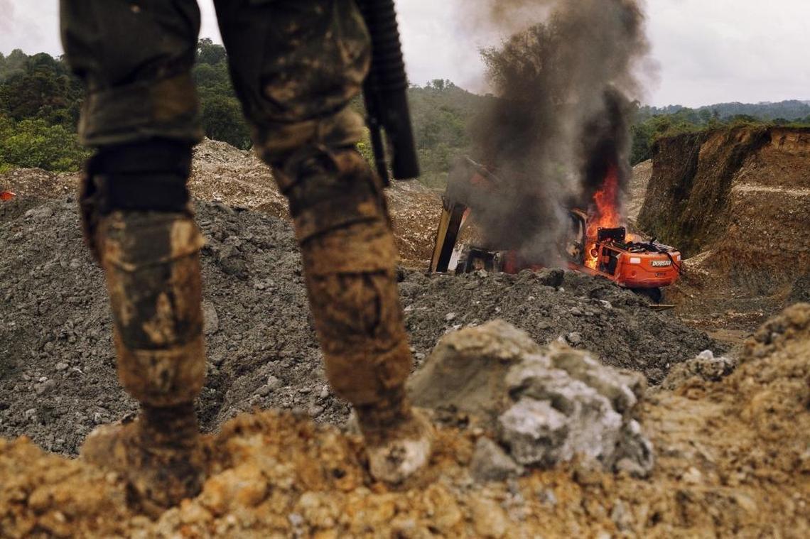 A policeman stands watch in southwestern Colombia after authorities destroyed backhoes involved in illegal mining operations.