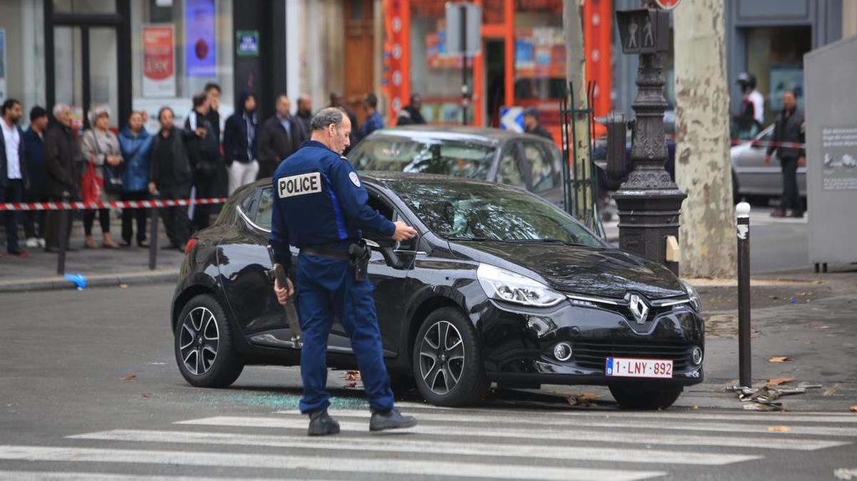 A police officer stands by a Renault Clio with Belgian license plates in Paris on Tuesday that could be linked to Friday’s attacks. The car was discovered near the commuter train line that links to France’s national stadium, which was a site targeted by three suicide bombers.