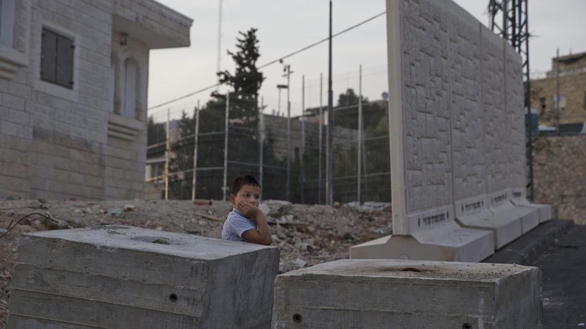 
A Palestinian boy stands by concrete barrier between the Arab neighborhood of Jabal Mukaber and the Jewish area of Armon Hanatziv in east Jerusalem on Sunday, Oct. 18, 2015. Israeli police say they have set up a concrete barrier between a Jewish and an Arab neighborhood in east Jerusalem amid soaring tensions. Police spokeswoman Luba Samri says Sunday the slabs were placed there for security reasons, without elaborating. Rocks and firebombs have often been hurled from the Arab area at houses in the Jewish neighborhood. 
