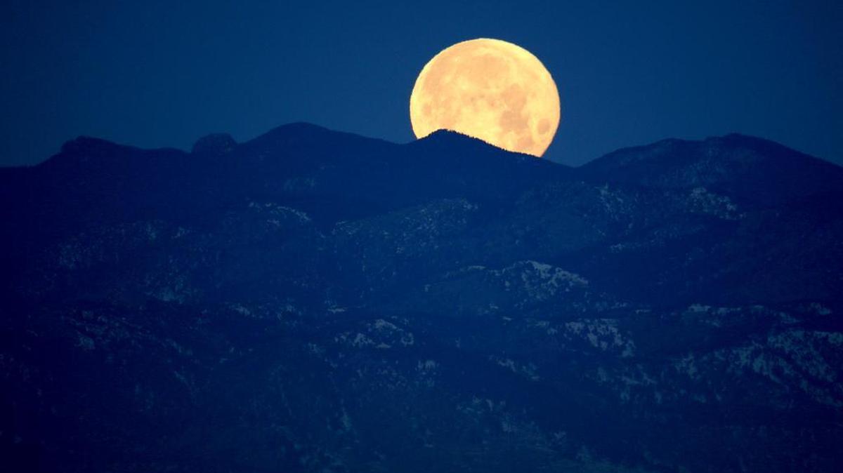 The full moon sets beyond the Rocky Mountains beyond Denver on Sunday. The moon may be the closest object to us in space, but scientists are still struggling to understand how it got there.