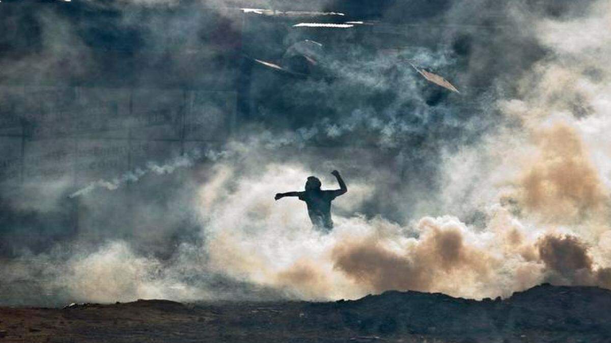 
In this file photo from March 16, 2014, a demonstrator partly shrouded by tear gas fired by Bolivarian National Guards prepares to throw a rock during clashes near Plaza Altamira in Caracas, Venezuela.
