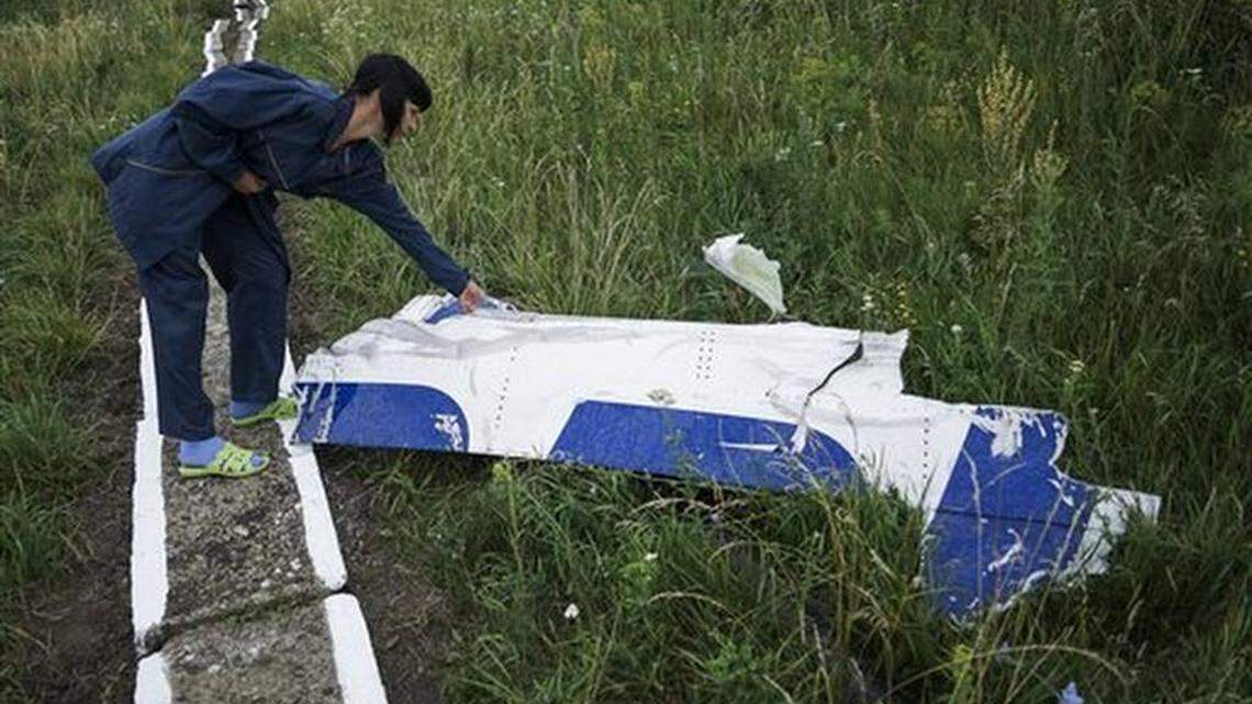 In a Tuesday, July 14, 2015 photo, an employee of water station examines large piece of MH17 plane, which had not been taken away at the Malaysian Airlines MH-17 plane crash site toward Hrabove village, eastern Ukraine. Memories of the downing of the Malaysian Airlines plane still haunt the residents of Hrabove, who remember the bodies that fell from the sky above their sleepy village in eastern Ukraine.