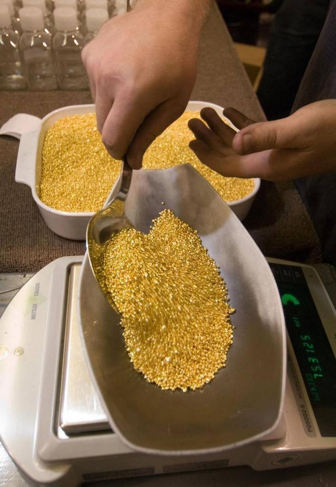 A worker scoops grains of pure gold onto a scale for weighing before packaging and shipment at Ohio Precious Metals in Jackson, Ohio, in 2006.